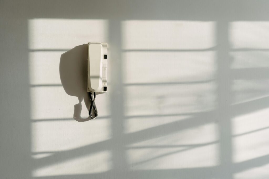 A minimalist intercom casting shadows on a white wall, creating a simple yet striking composition.
